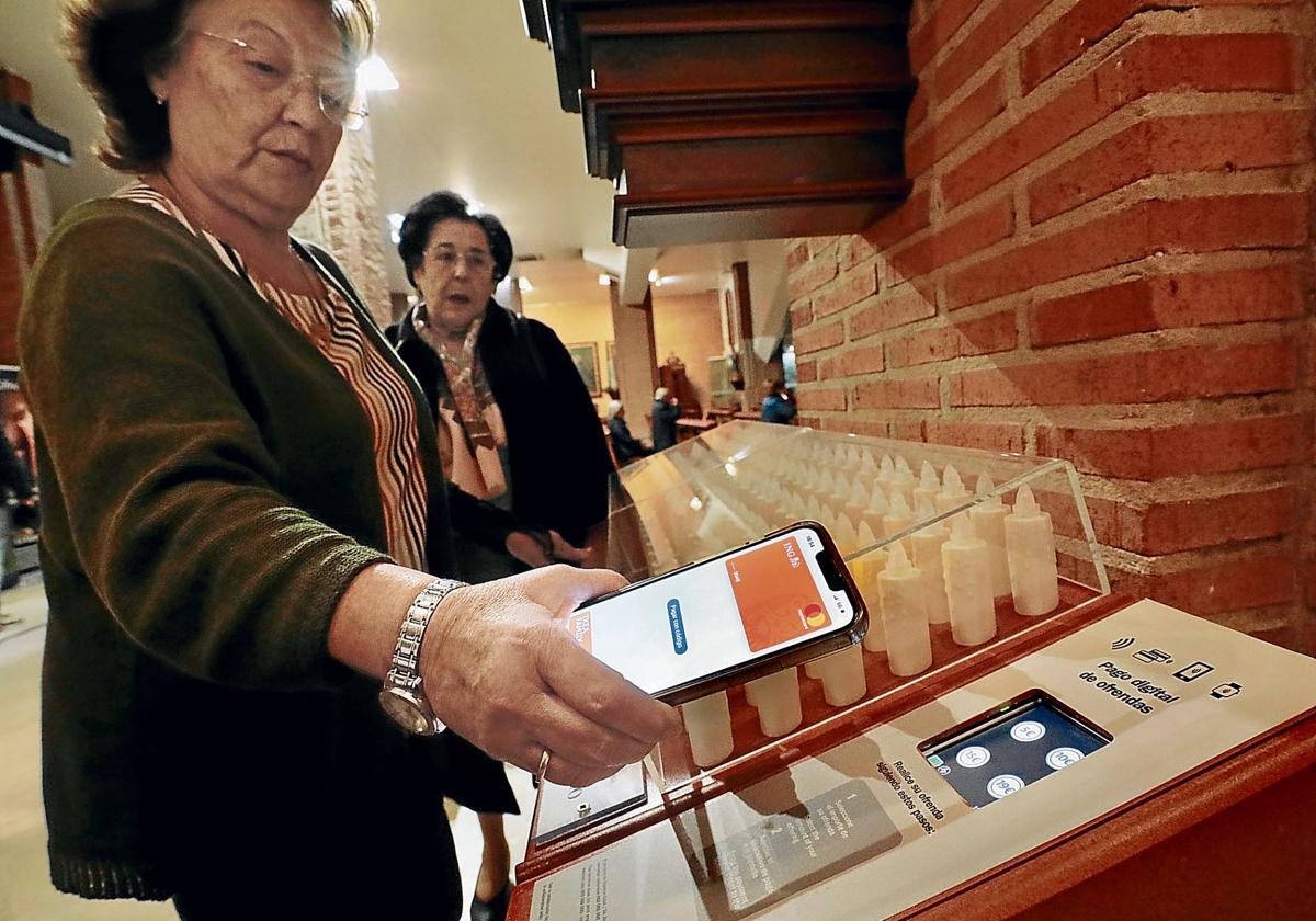 Una feligresa aporta una limosna a través de su móvil en una iglesia.