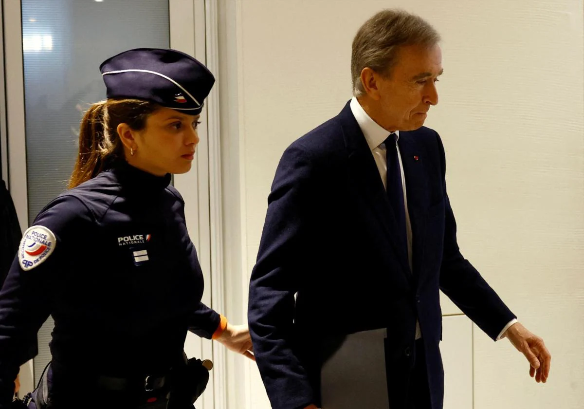 El magnate Bernard Arnault, custodiado por una agente a su llegada a la audiencia del Tribunal de París para testificar.