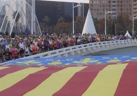 Corredores pasan junto a la enorme Senyera desplegada en el puente de Monteolivete.