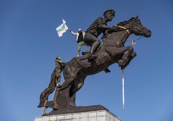 Un insurgente ondea una bandera encaramado a la estatua de Bassel al Assad antes de su derribo en Alepo.