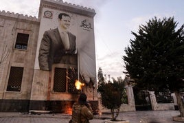 Un rebelde dispara contra un retrato de Al Assad en una calle de Hama.