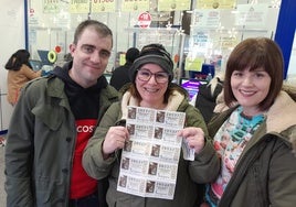 Tania, de Santoña, junto a sus amigos Alberto y Cristina, muestran triunfales sus décimos de Doña Manolita tras horas de cola.