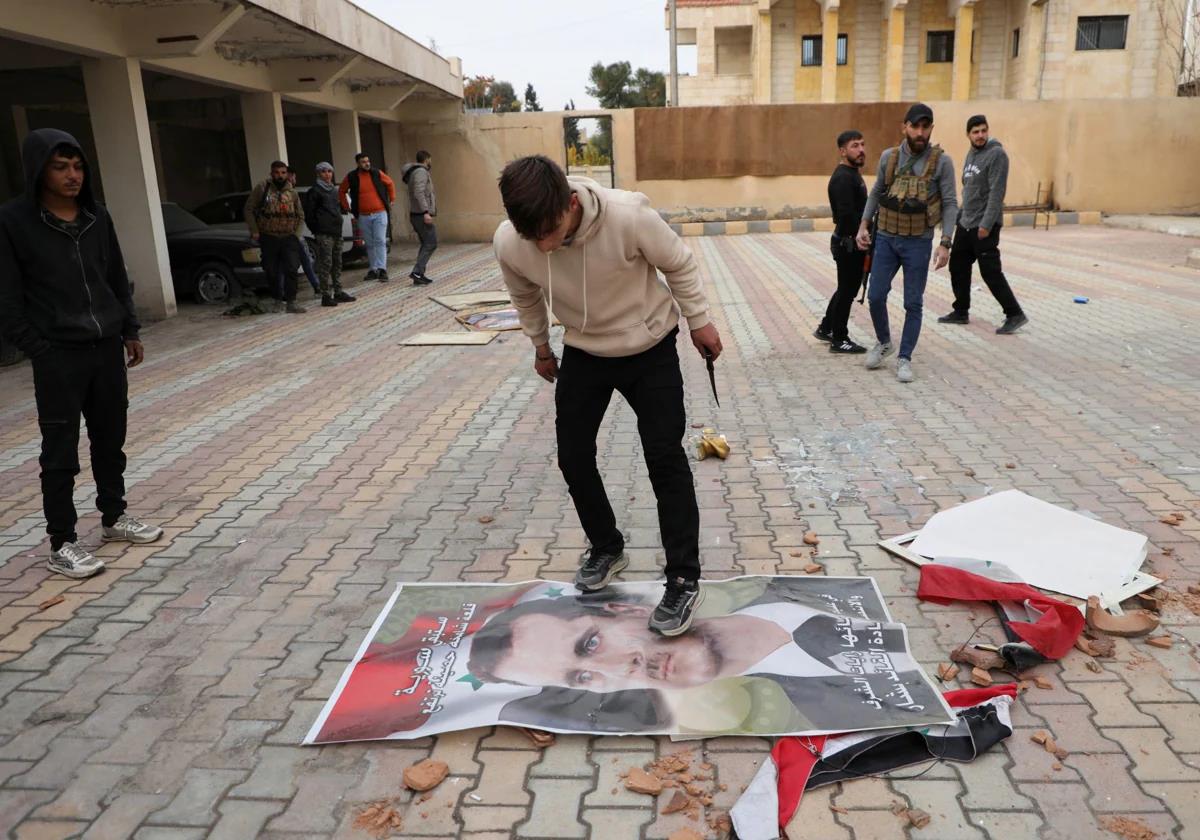 Un joven pisotea un retrato de Al Assad.