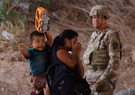 Migrantes se paran cerca del río Bravo después de cruzar la frontera para solicitar asilo en Estados Unidos, vista desde Ciudad Juárez.