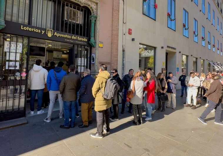 Decenas de personas esperan para comprar los últimos décimos en la administración El Gato Negro en Sevilla.