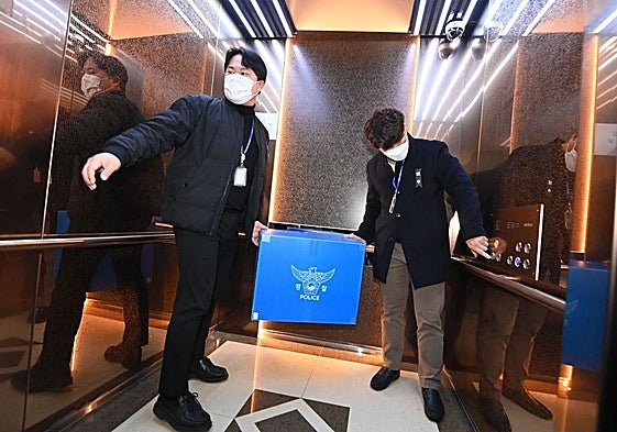 Agentes de la Policía surcoreana se llevan material del aeropuerto de Muan tras realizar un registro.