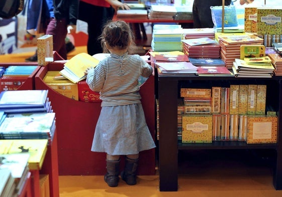 Una niña hojea los álbumes ilustrados en la sección infantil de una librería.