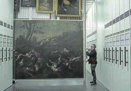 Mario Núñez, técnico de 'La brigada', descorre uno de los peines con cuadros de distintos formatos que se conservan en los almacenes del Museo del Prado.