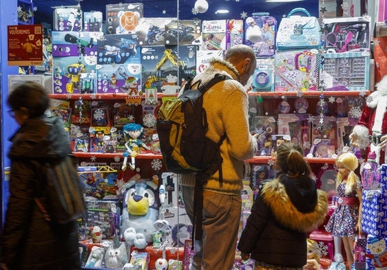 Un padre y su hija observan el escaparate de una juguetería.