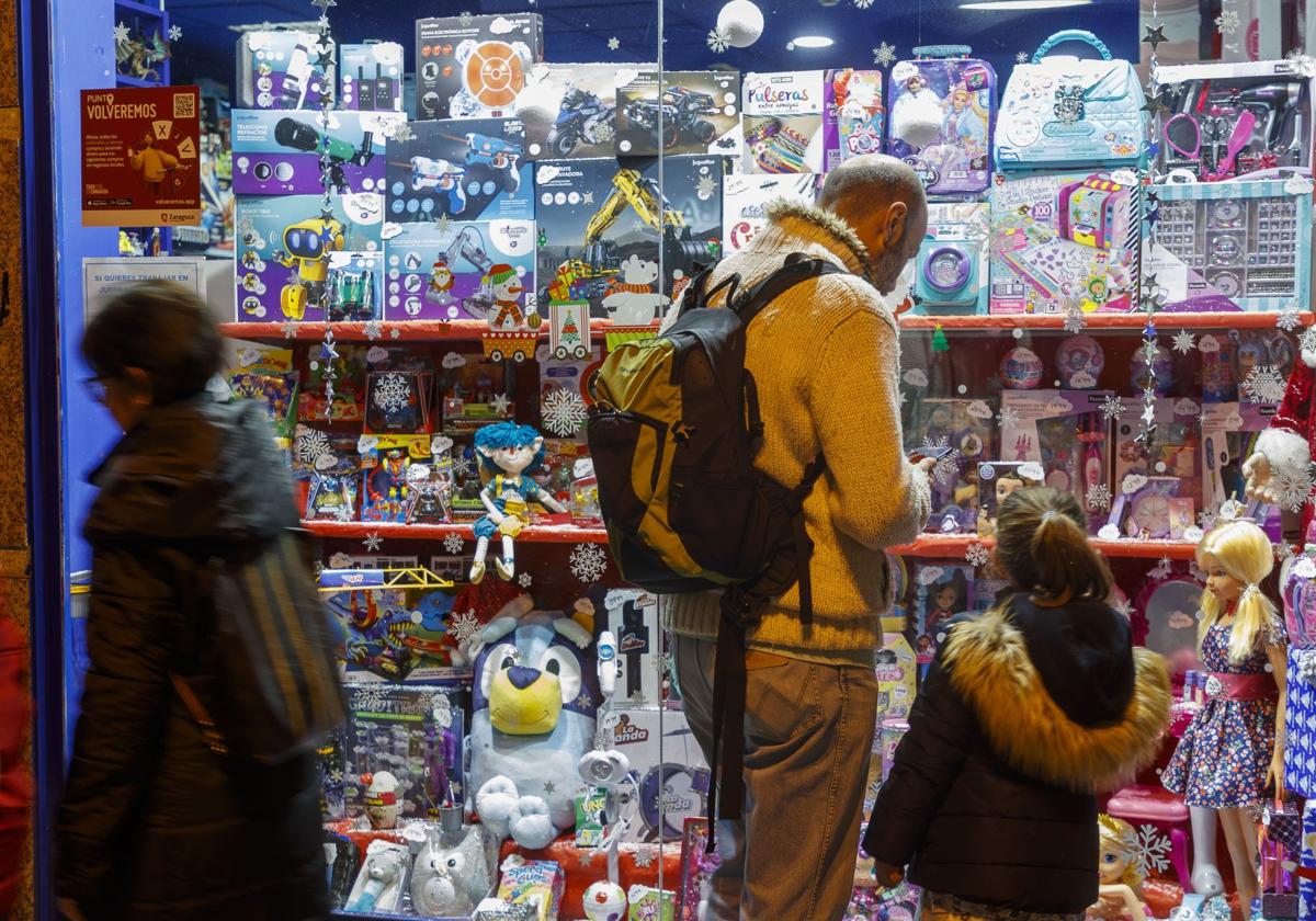 Un padre y su hija observan el escaparate de una juguetería.