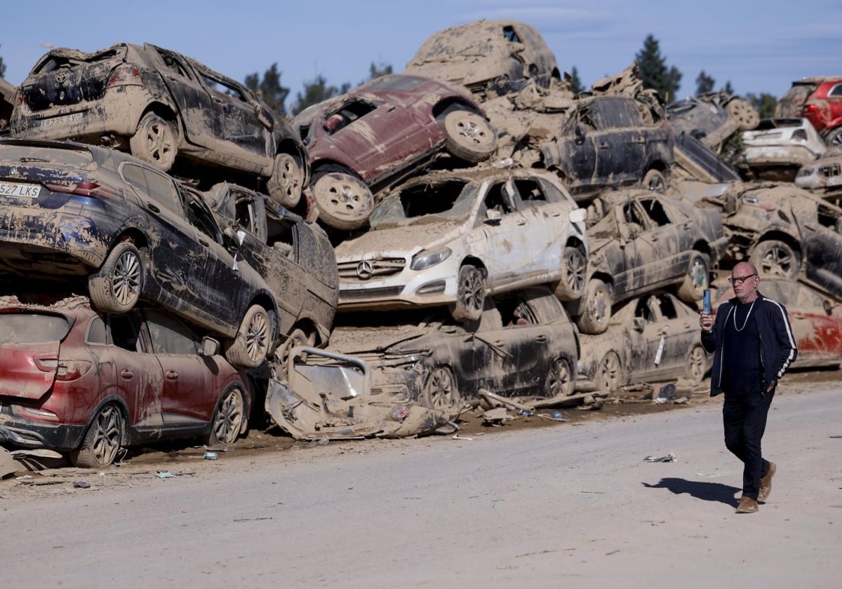 Un hombre pasa ante los innumerables coches apilados en Catarroja, tres semanas después de la tragedia provocada por la dana