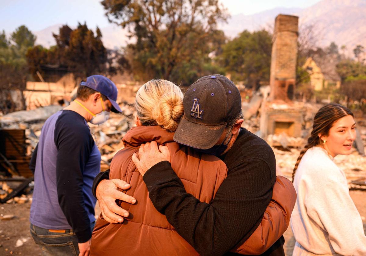 Dos miembros de familia se abrazan al ver que la casa en la que vivían ha sido destruida por uno de los incendios.