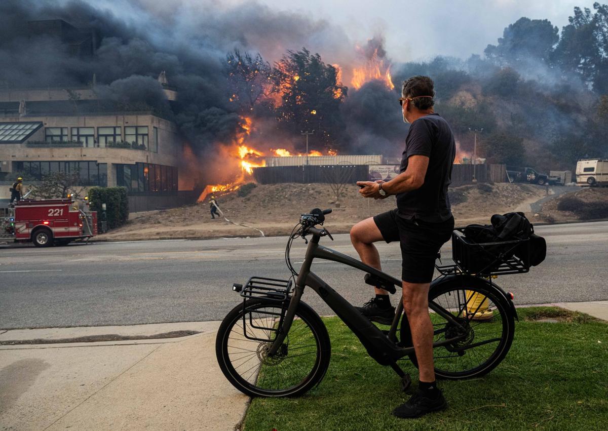 Imagen secundaria 1 - Arriba, la vista aérea de Pacific Palisades, totalmente reducido a escombros. En el medio, un residente observa desde la acera las llamas que devoran las montañas, y abajo, una vivienda destruida al lado de la playa. 