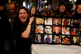 Una mujer muestra los retratos de un grupo de rehenes en una manifestación en Jerusalén.