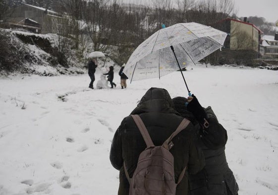 Niños hacen un muñeco de nieve en una zona de la montaña gallega.