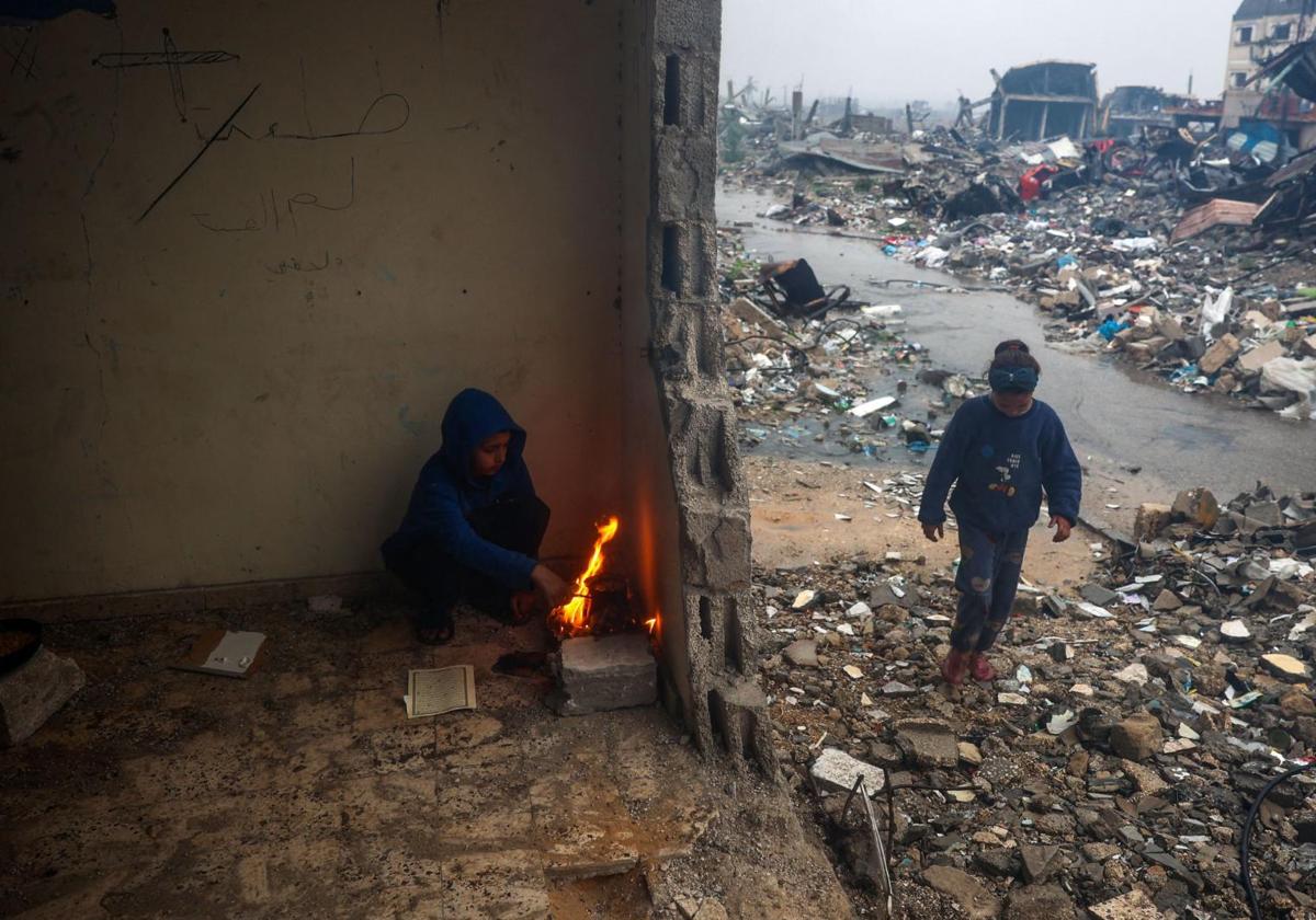 Niños palestinos tratan de calentarse en medio de las ruinas de Ciudad de Gaza.