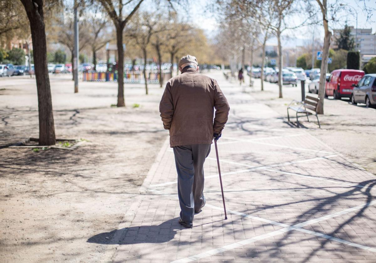 Un anciano camina bajo el sol.