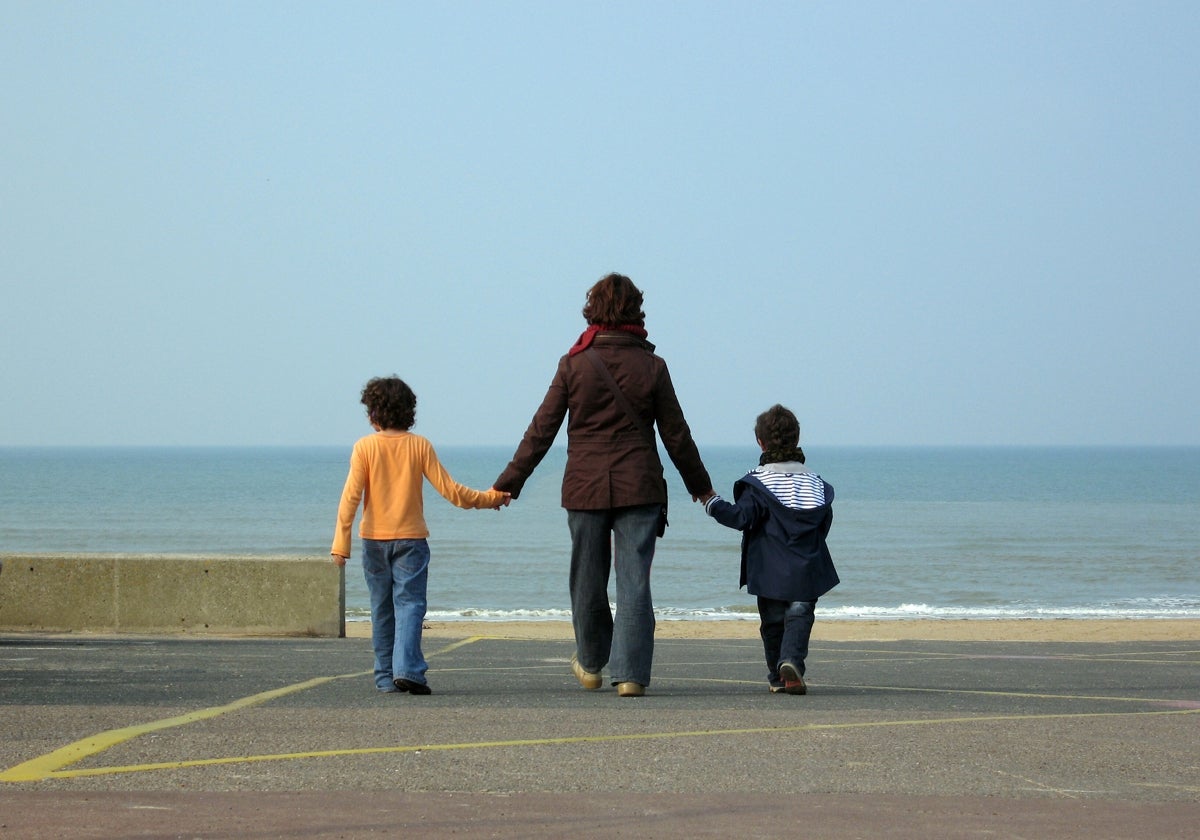 Una madre, junto a sus dos hijos, observa el mar.