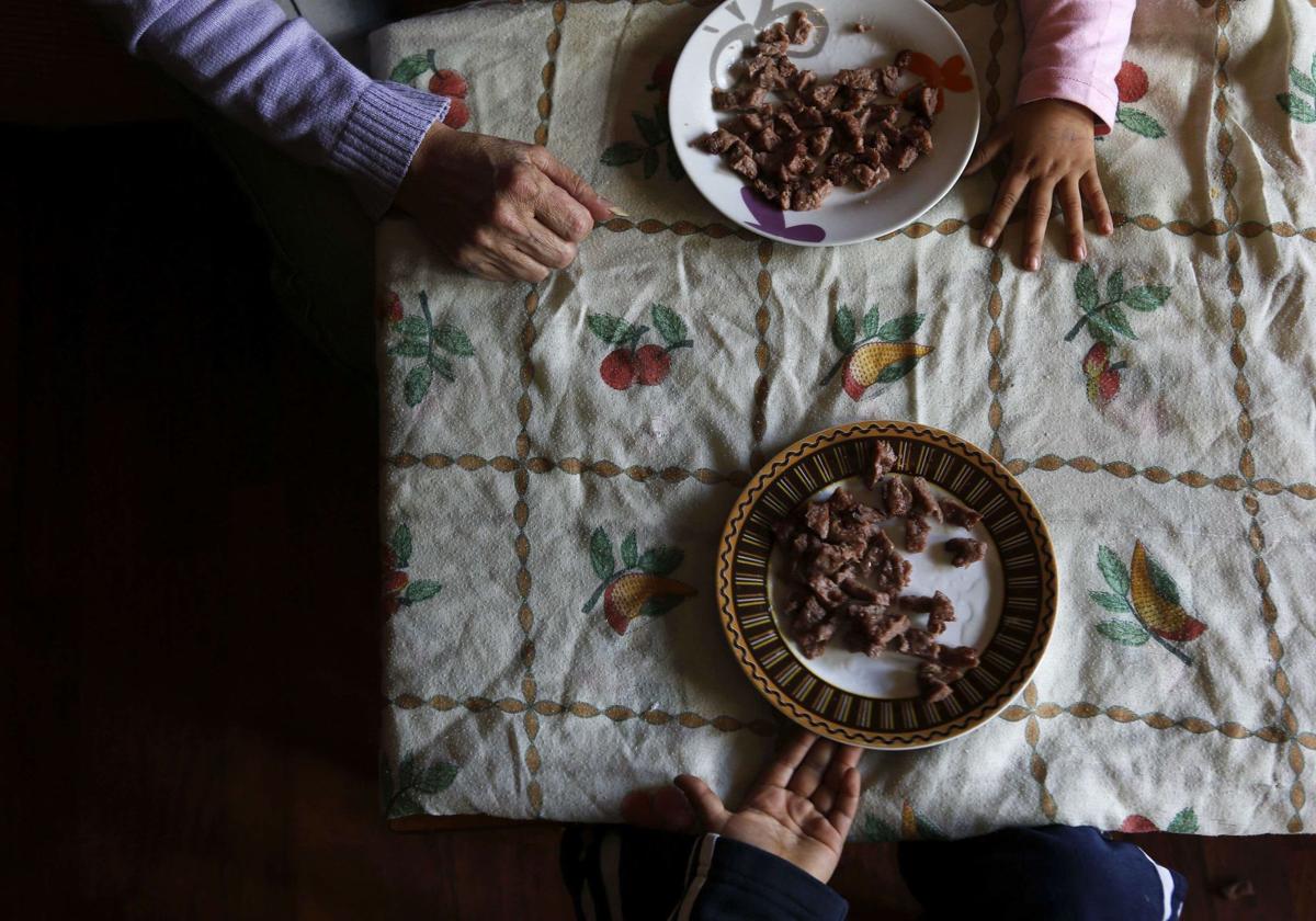 Una madre en situación de vulnerabilidad pone la comida a sus hijos.