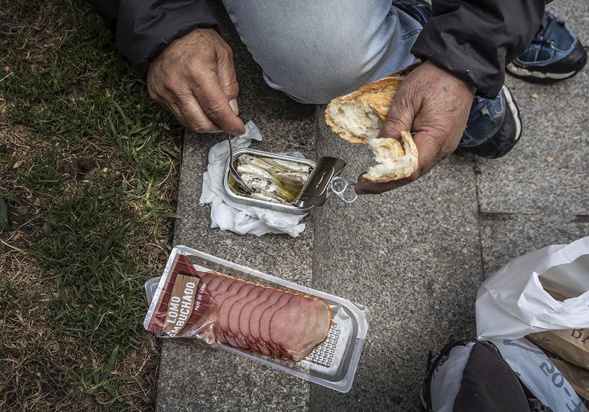 Una persona sin hogar se hace un bocadillo.