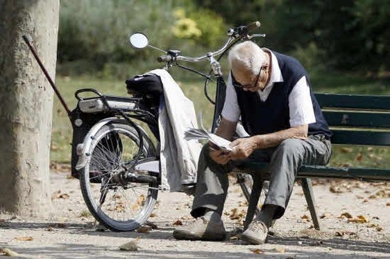 Un jubilado lee el periódico en un parque.