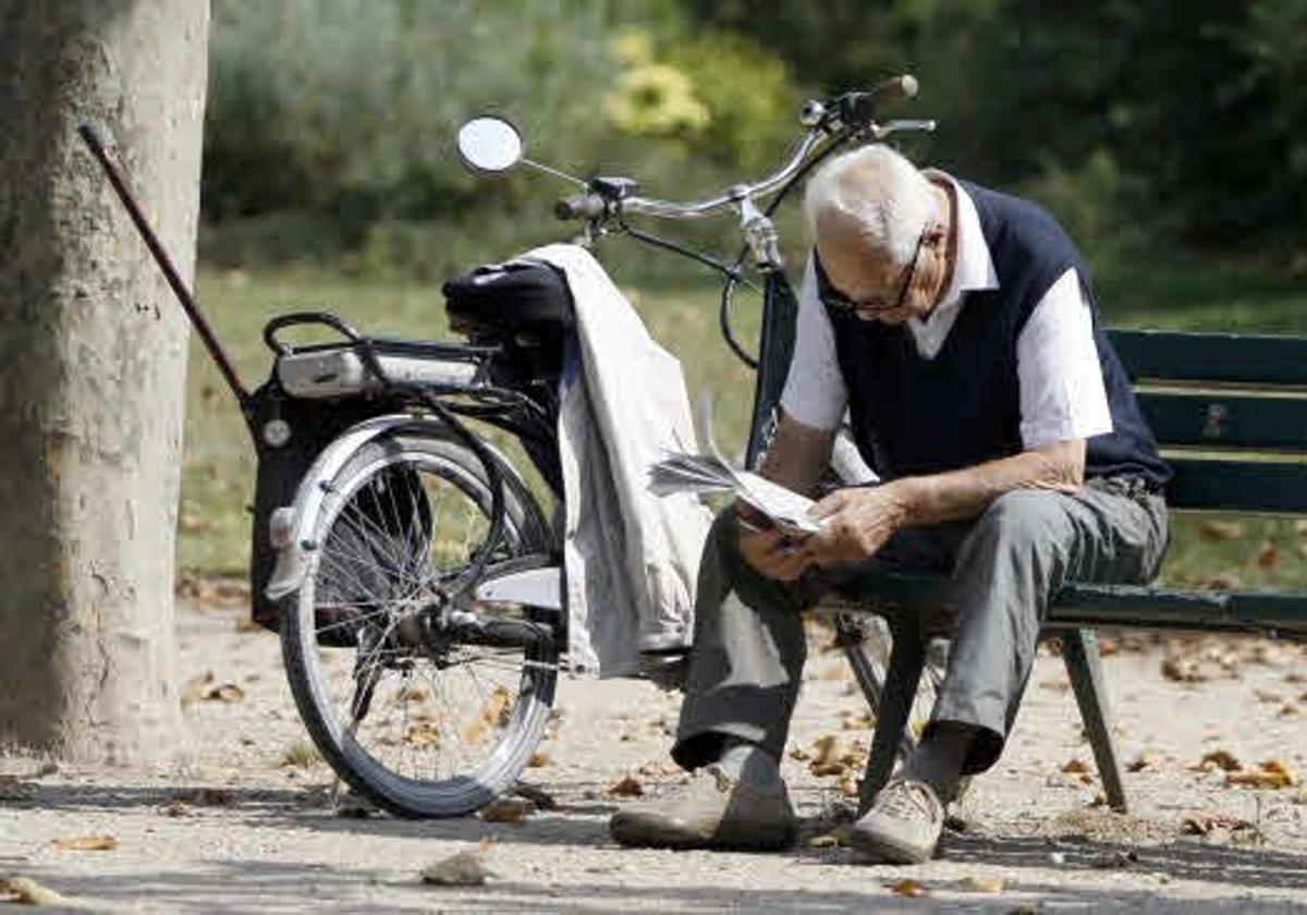 Un jubilado lee el periódico en un parque.