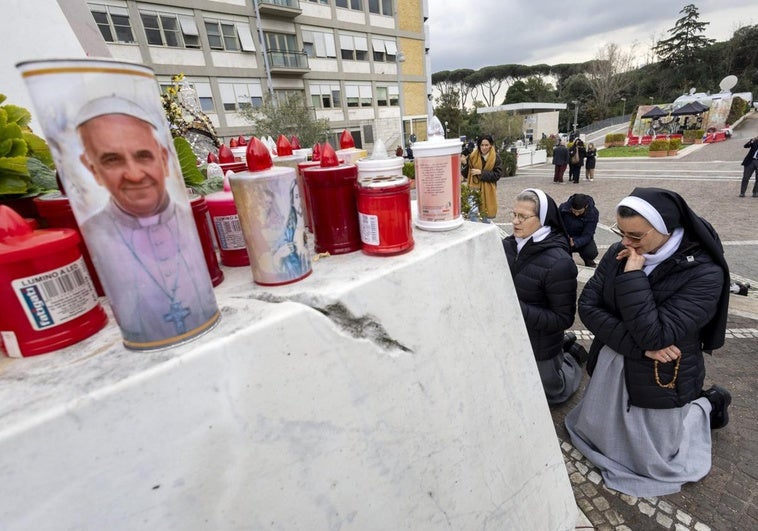 Dos monjas rezan bajo la estatua del Papa Juan Pablo II, en el policlínico Gemelli, donde está hospitalizado el Papa Francisco en Roma.