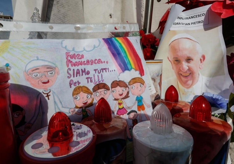 Un dibujo y una imagen del Papa Francisco, bajo la estatua del Papa Juan Pablo II en el exterior del Hospital Agostino Gemelli.