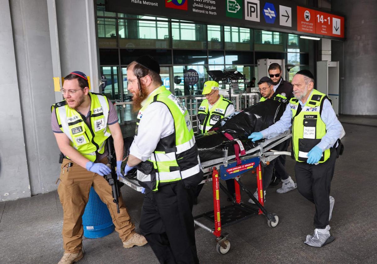 Miembros de los servicios de emergencias transportan el cuerpo del presunto autor del apuñalamiento en una estación de autobuses en Haifa.