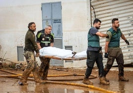 Dos guardia civles y dos voluntarios trasladan un cuerpo en la localidad valenciana de Catarroja, una de las más afectadas por la dana.