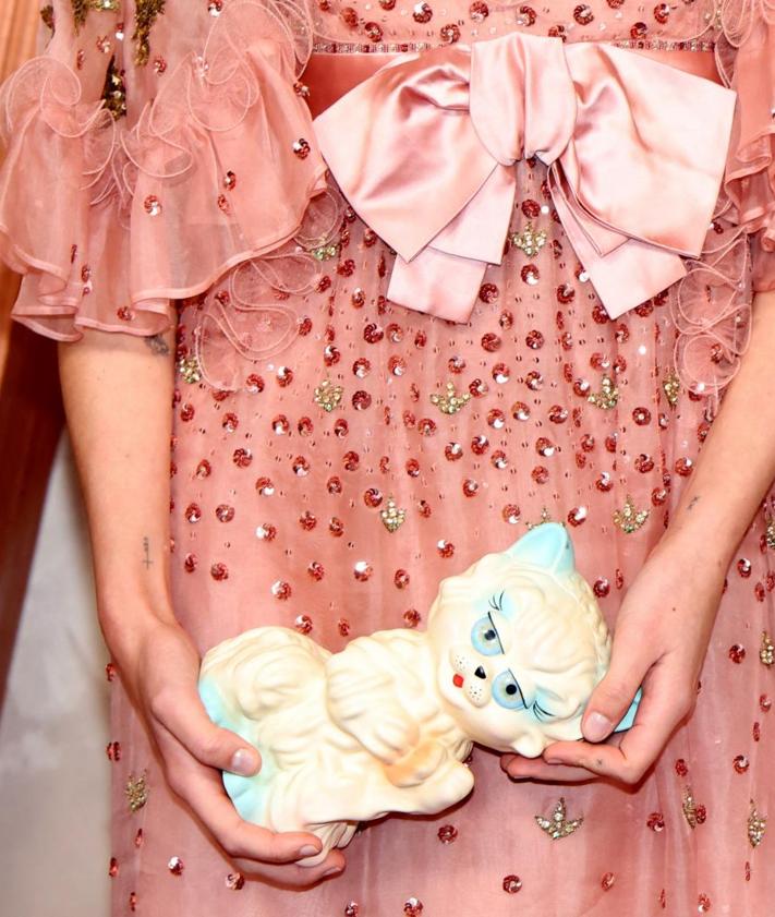Imagen secundaria 2 - Arriba, imagen de Ariana Grande en la que se ve puede ver el zapato de su espalda. Abajo, detalle de las uñas de Cynthia Erivo y el bolso de gato de Charlotte Lawrence.