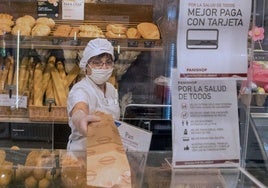Una panadera atendiendo a clientes en su local.
