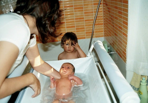 Una mujer baña a sus hijos en su domicilio.