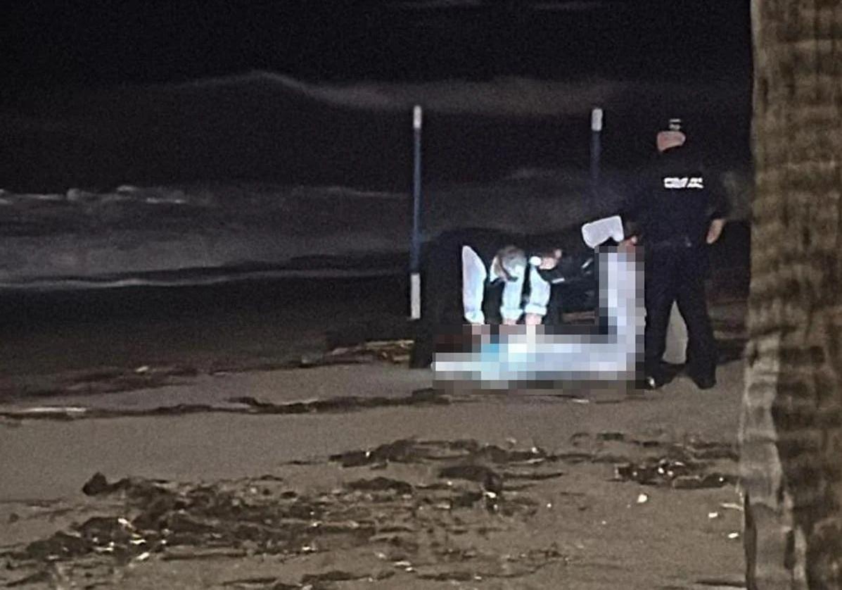 Imagen de los agentes con el cadáver en la playa.