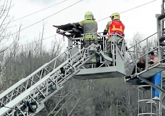 Los dos testigos que acudieron a socorrer a los menores sostienen al más pequeño en la plataforma de la torre mientras aguardan el rescate de los bomberos.