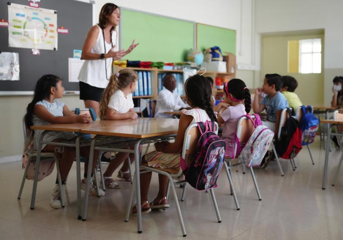 Varios alumnos en una clase atienden a una profesora