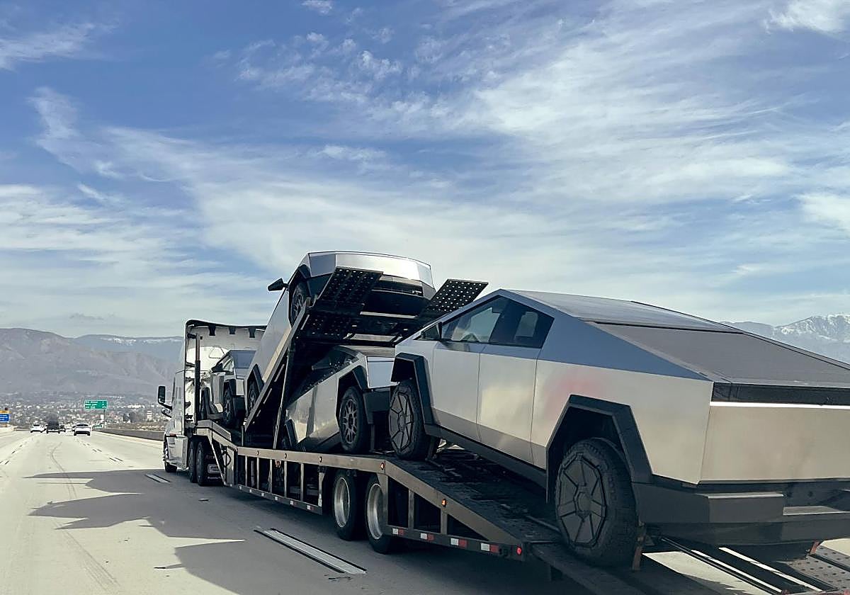Un portavehículos transporta cuatro nuevos Tesla Cybertrucks por la autopista de Highland, California