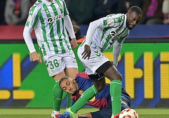 Sabaly se lleva el balón con Raphinha en el suelo.