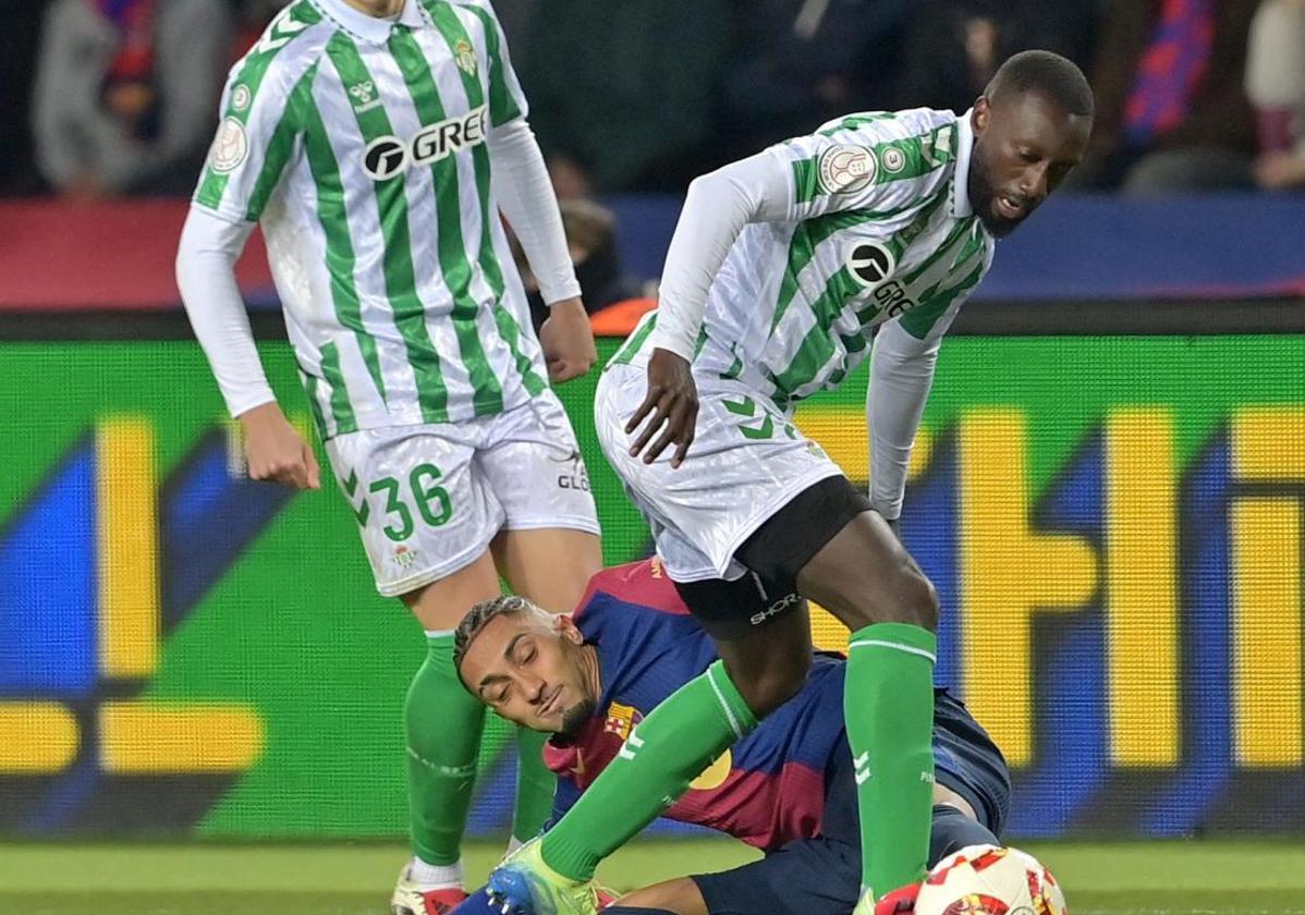 Sabaly se lleva el balón con Raphinha en el suelo.