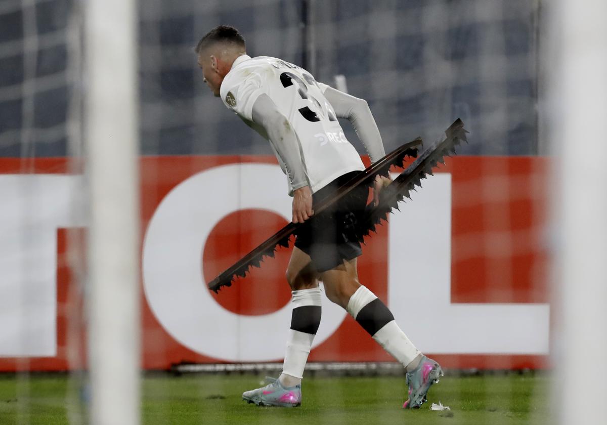 Un jugador del Colo Colo retira del césped del Estadio Monumental varios objetos lanzados.