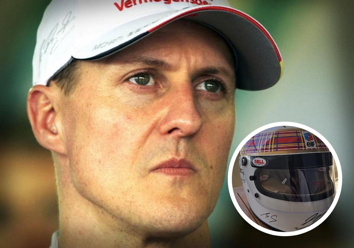 Michael Schumacher, with his wife's help, signs a helmet for a charitable cause