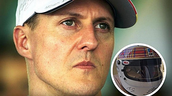Michael Schumacher, con ayuda de su mujer, firma un casco para una causa benéfica