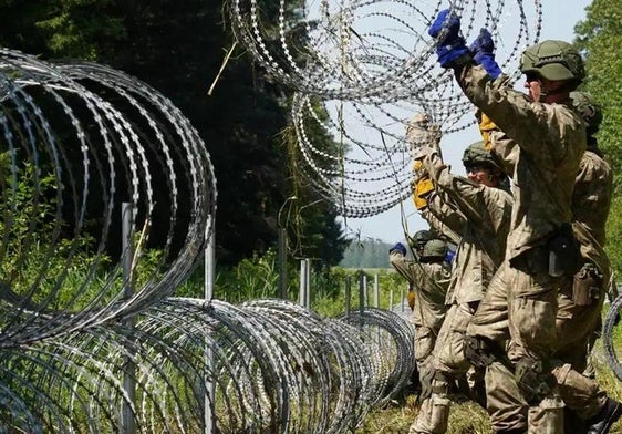Soldados lituanos colocan alambradas para delimitar y proteger la frontera con Bielorrusia.