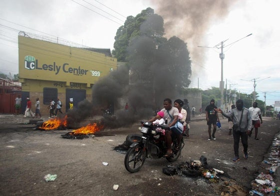 Un hombre conduce su motocicleta junto a una barricada en Puerto Príncipe.
