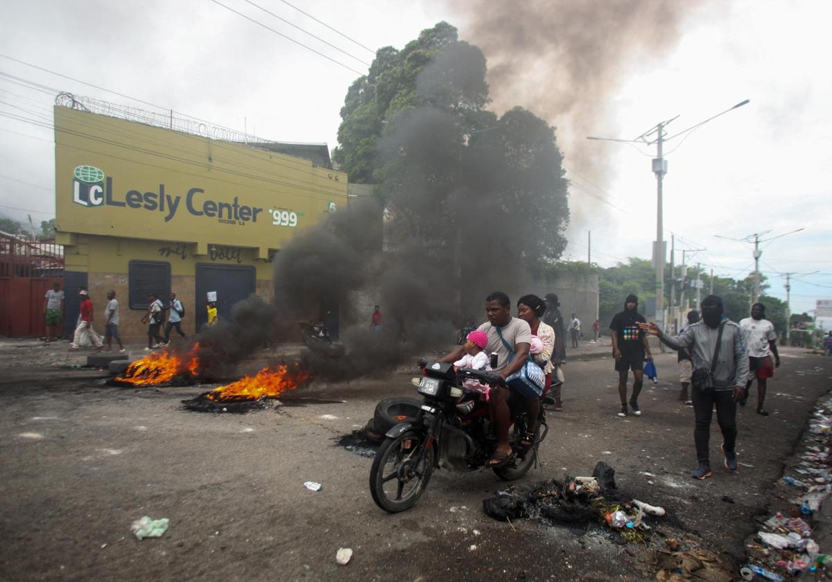 Un hombre conduce su motocicleta junto a una barricada en Puerto Príncipe.