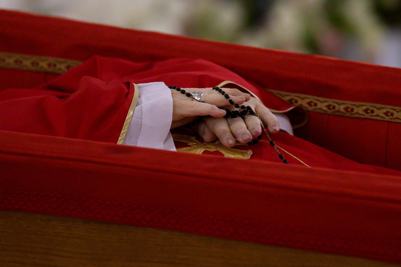En las manos, sostiene el rosario.