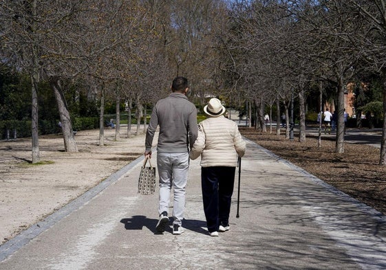 Un jubilado pasea por un parque.