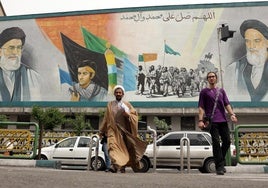 Un clérigo iraní camina junto a un enorme mural del Líder Supremo, el ayatolá Alí Jamenei, en una calle de Teherán.