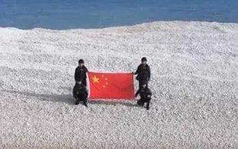 Los militares chinos muestran la bandera en Teixian.
