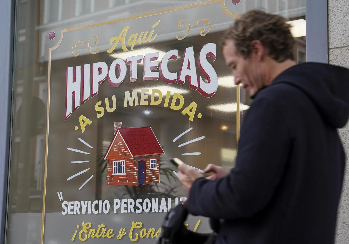 Un hombre camina junto a un escaparate hipotecario.
